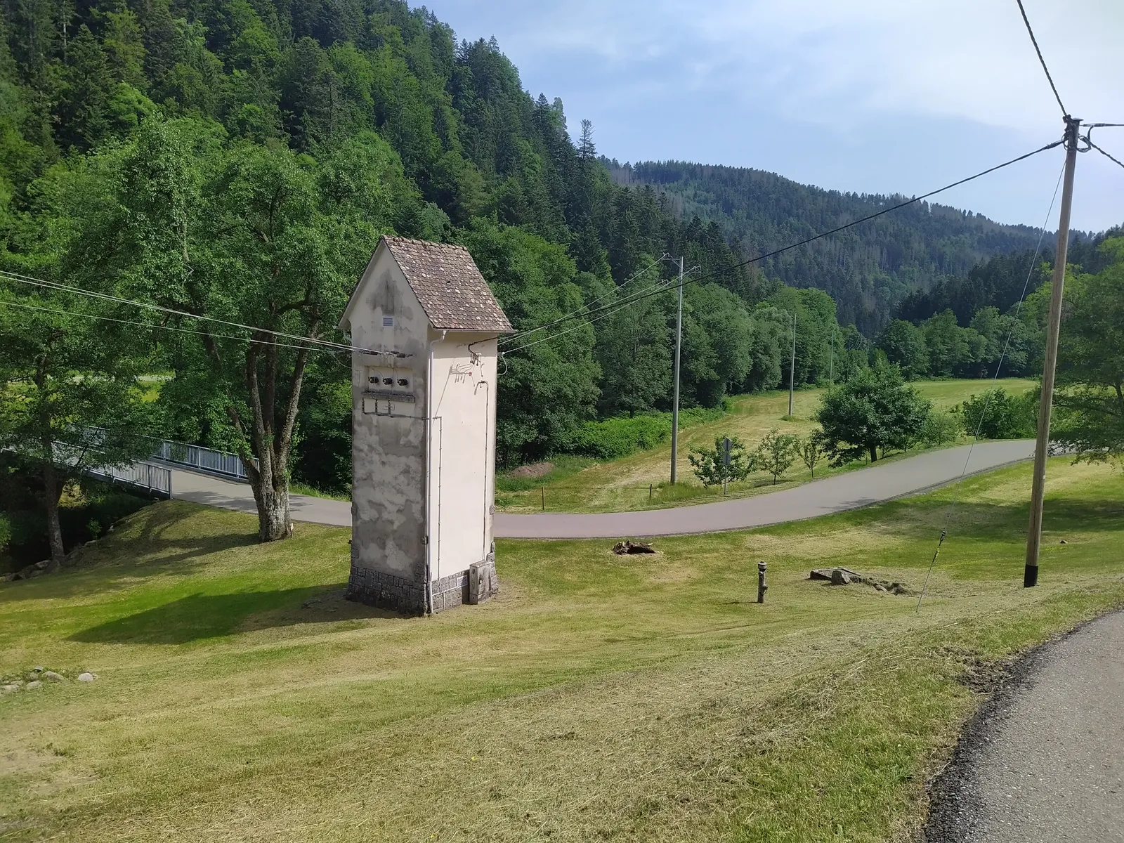 Ein Trafoturm am Waldrand im Südschwarzwald, Stromleitungen führen ins Tal.